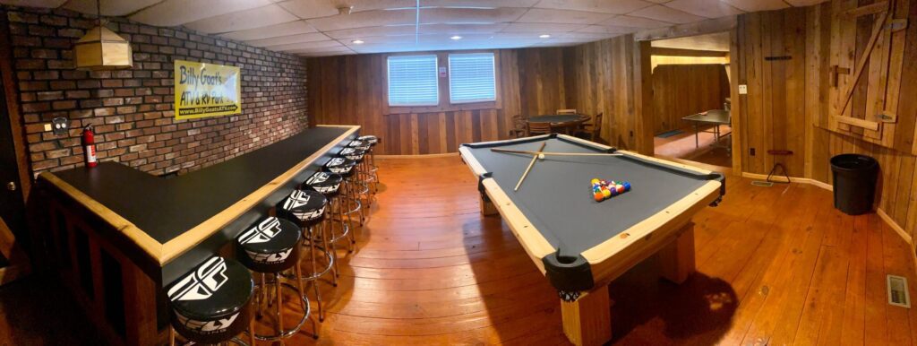 A room with a pool table and bar stools in a 6 Bed Room Hatfield McCoy Trail House Rental.