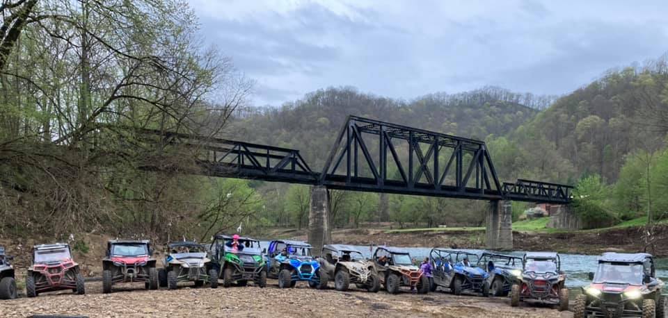 Group of mountain top adventure cars near river.