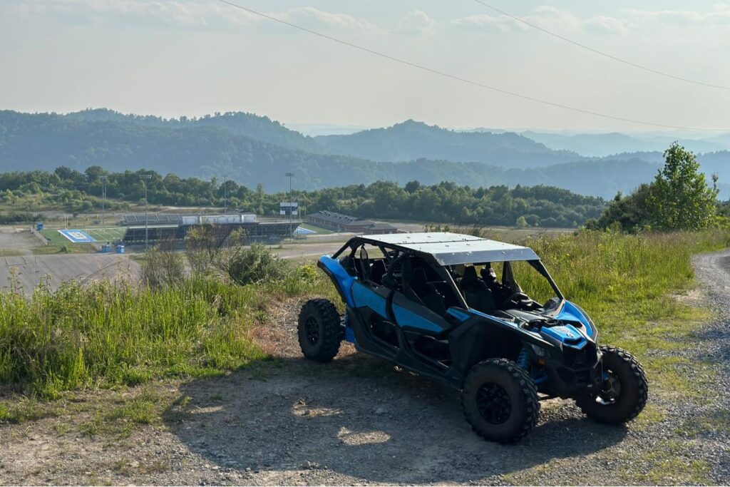 A blue Hatfield McCoy SXS Rentals can-am maverick x rs parked on a dirt road.