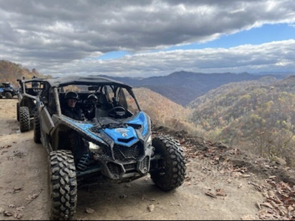 Two Can-Am Maverick UTVs on a dirt trail with Hatfield McCoy SXS Rentals.