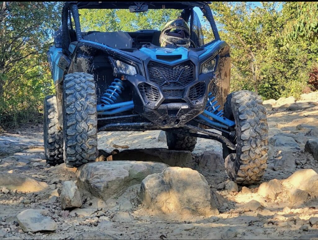 A blue Hatfield McCoy SXS Rentals can-am maverick x rt on a rocky trail.