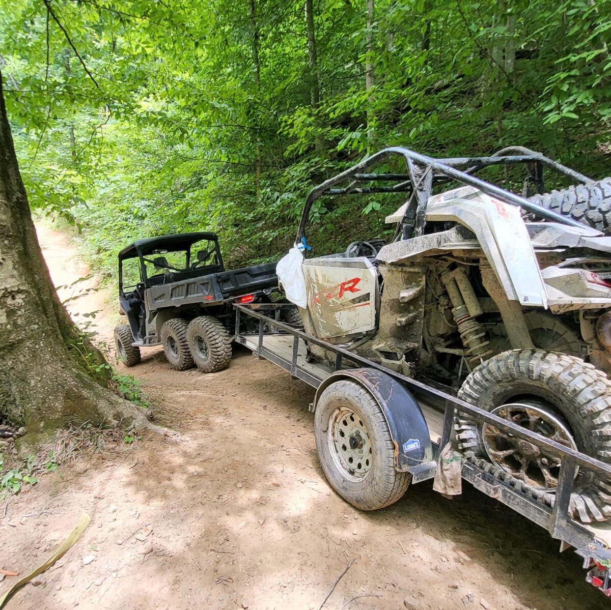 Two off-road vehicles on a trailer in a forest.